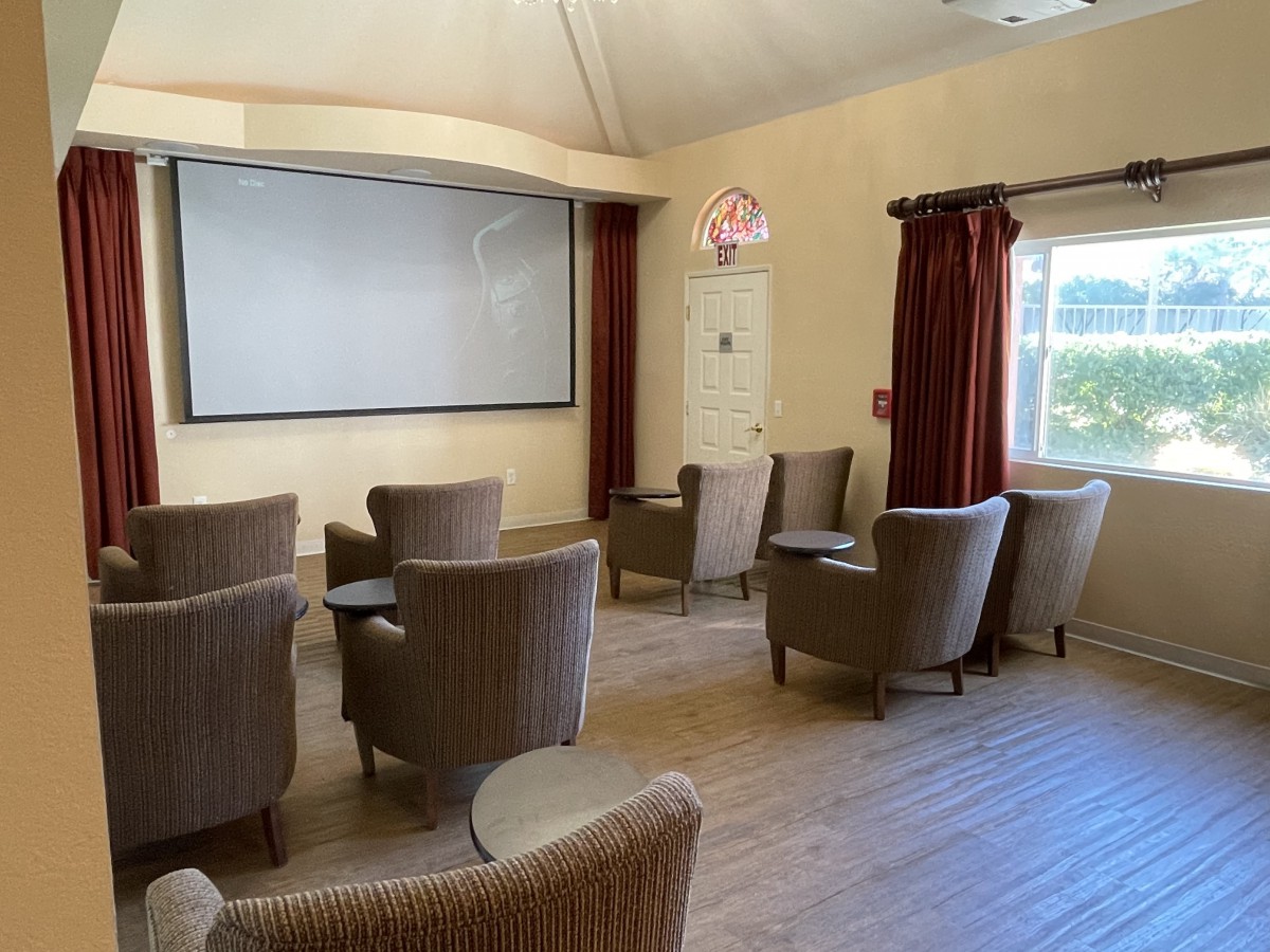 A cozy lounge area with armchairs arranged in front of a projector screen.