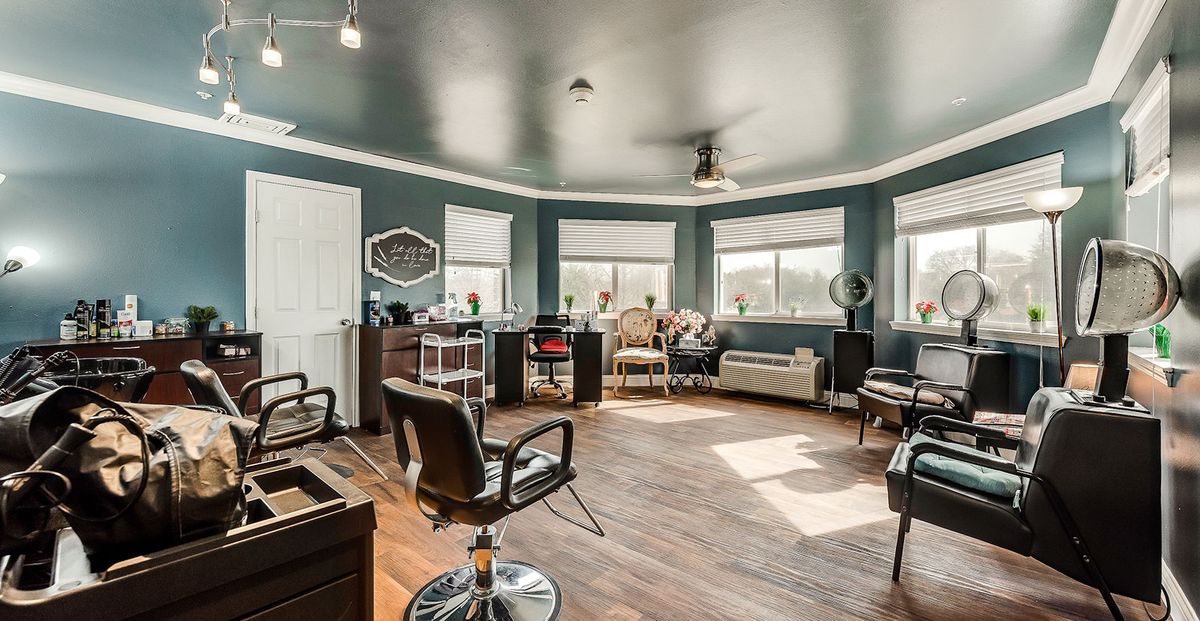 A spacious and modern hair salon with stylish chairs and ample natural light from large windows.