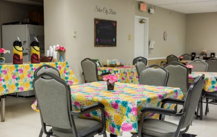 A brightly decorated dining area with tables covered in colorful floral tablecloths and chairs arranged around them.
