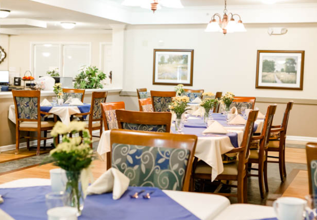A cozy dining room with neatly arranged tables and floral decorations.