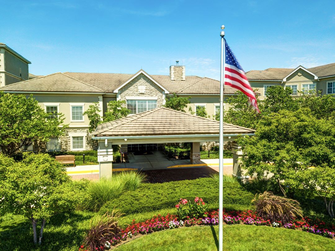 A well-maintained building with a U.S. flag, surrounded by lush greenery and gardens.