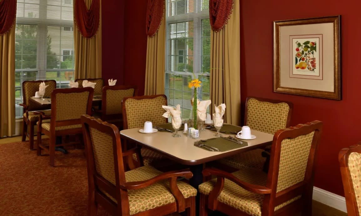 An elegantly set dining table in a formal restaurant with plush chairs and decorative curtains.