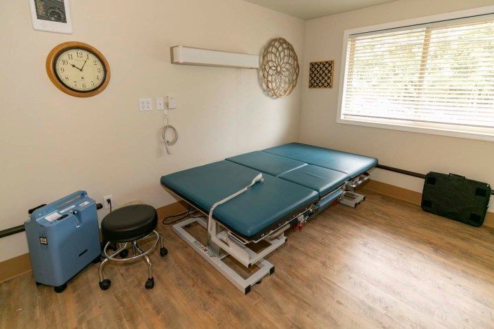A treatment room with a medical examination table and stool.