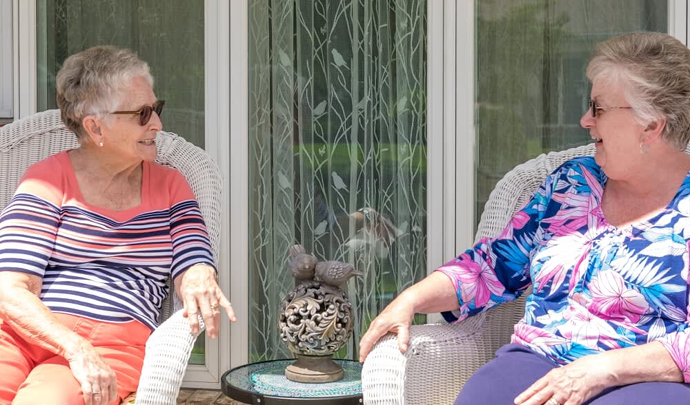 Two people sitting and chatting on a patio in a casual setting.