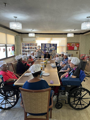 Residents of a care facility engaged in a group activity around a dining table.