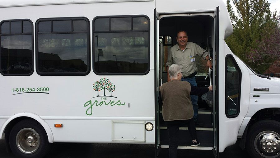 People boarding a bus with 'groves' logo on the side.