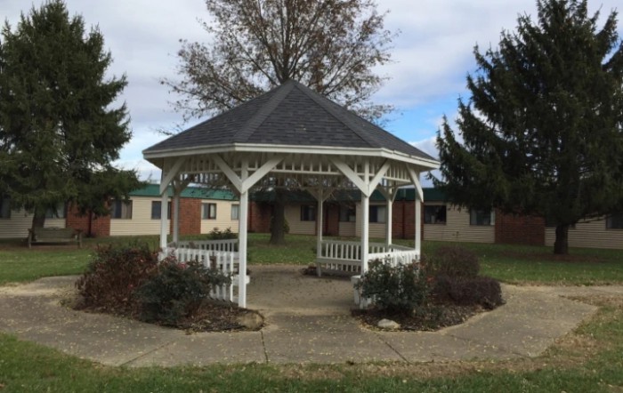 A white gazebo surrounded by greenery and situated in a park setting.