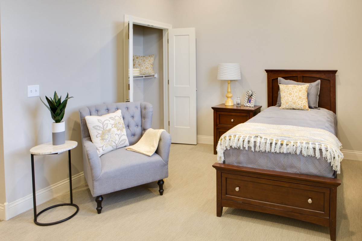 A cozy bedroom with a comfortable armchair and well-made bed.