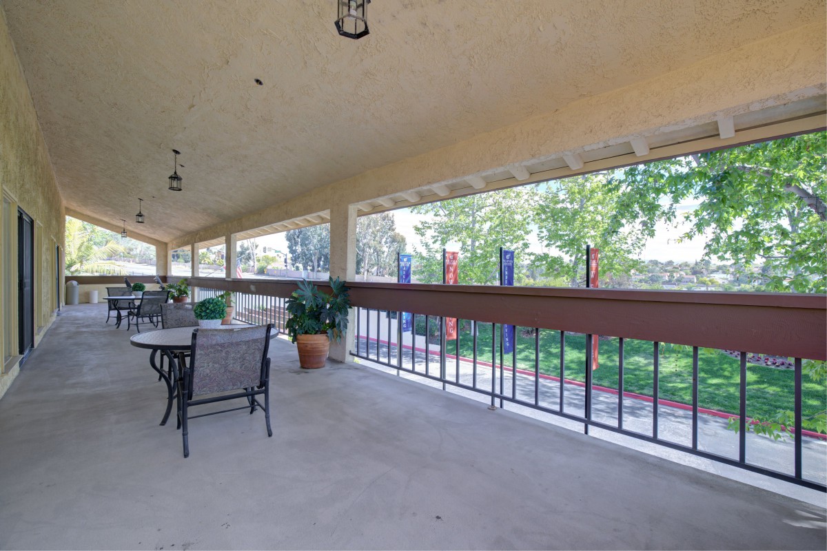 A spacious covered patio with outdoor seating and a view of the garden.