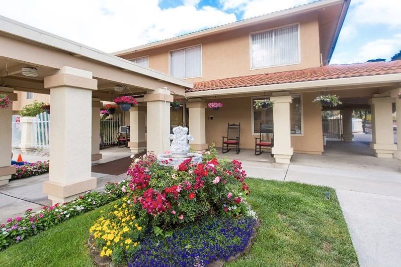 A two-story house with a well-maintained garden featuring colorful flowers.