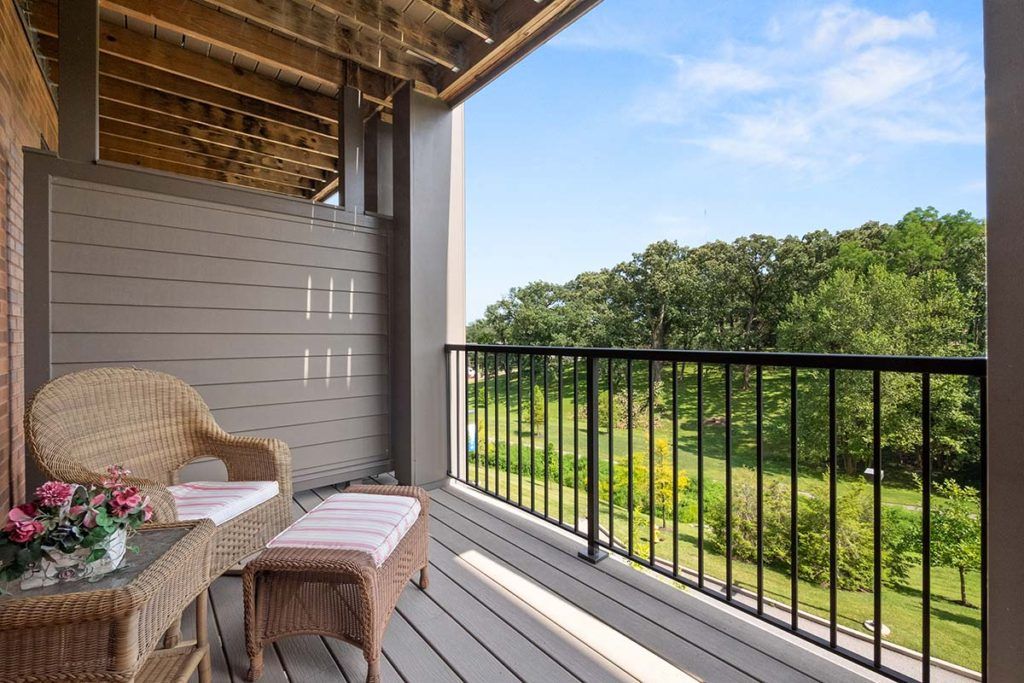 A cozy balcony with outdoor seating overlooking a lush green landscape.