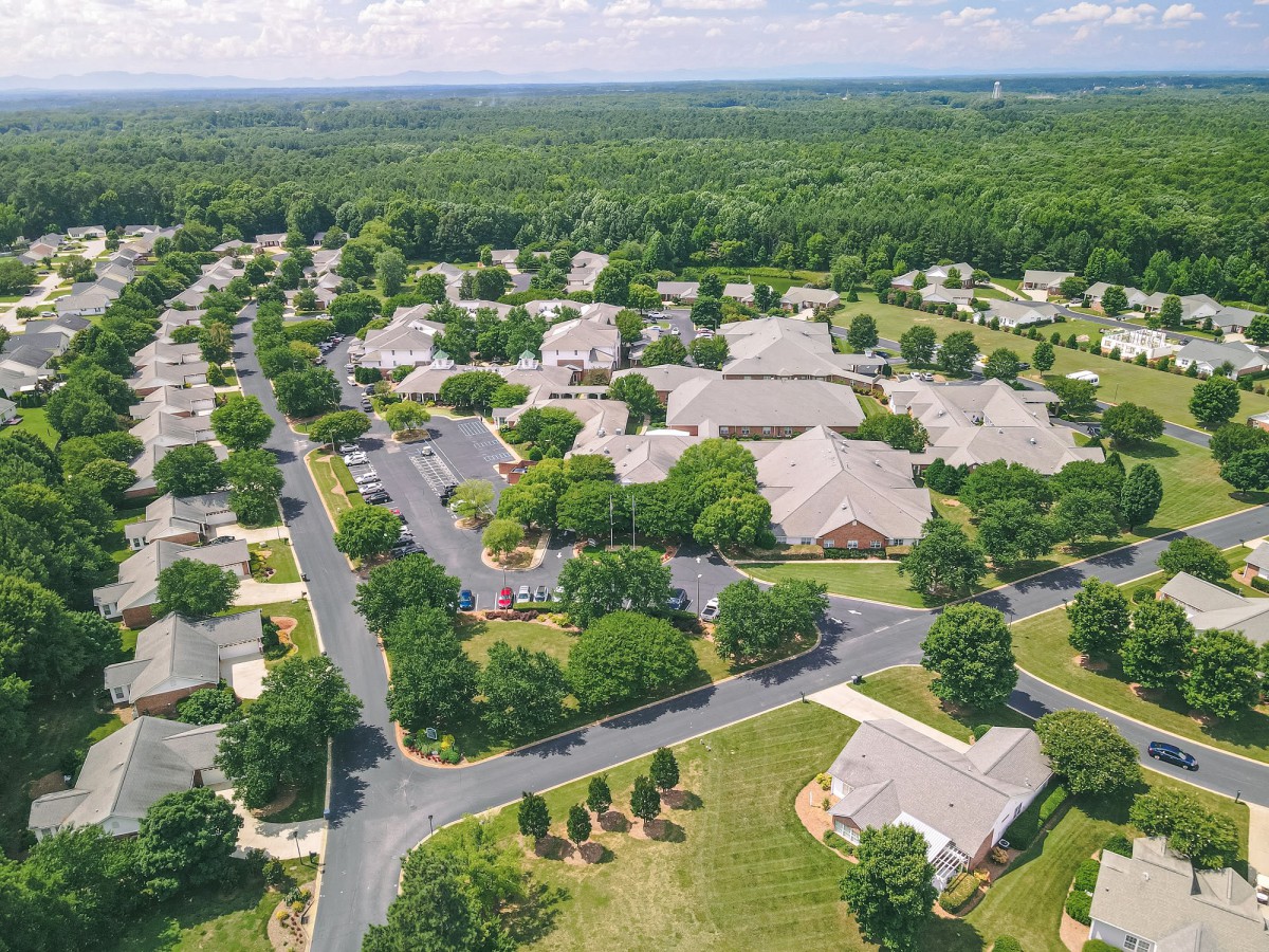 An aerial view of a suburban neighborhood with tree-lined streets and houses.