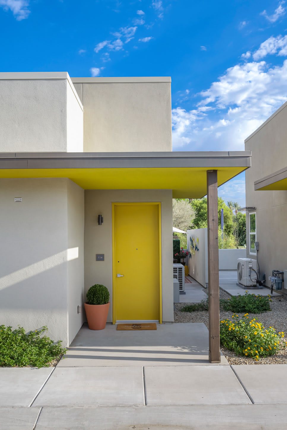 A modern home entrance with a vibrant yellow door and minimalist design.