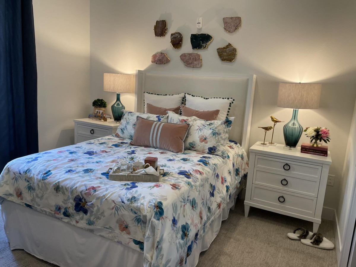 A cozy bedroom with patterned bedding, stylish lamps, and decorative wall accents.