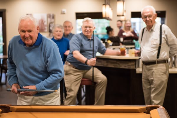 A group of elderly men enjoying a game of billiards in a social setting.
