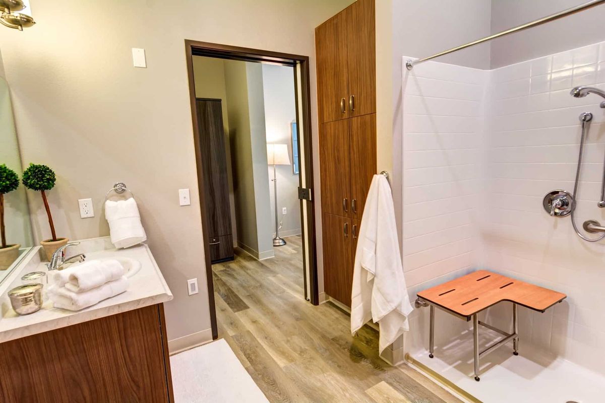 A modern bathroom with wooden flooring, featuring a shower area and neatly arranged towels.