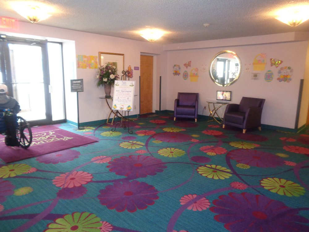 A brightly decorated lobby area with colorful floral carpeting, purple chairs, and a wall mirror.