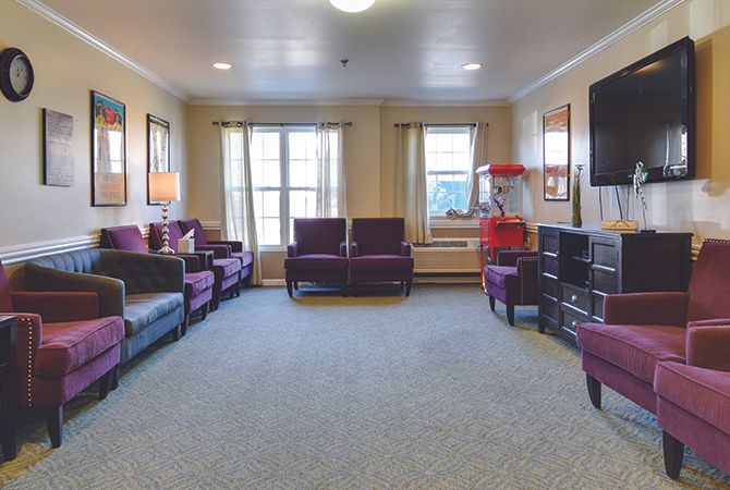 A cozy living room with multiple seating options, a TV, and a popcorn machine.