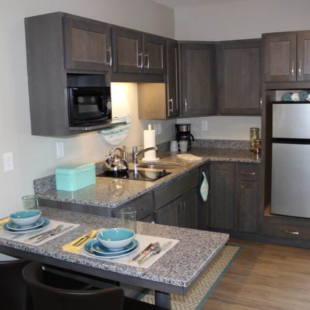 A modern kitchen with dark cabinetry and a small dining area.