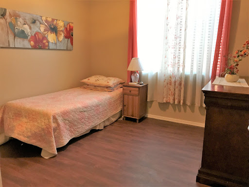 A cozy and minimalistic bedroom with a single bed, warm lighting, and decorative artwork.