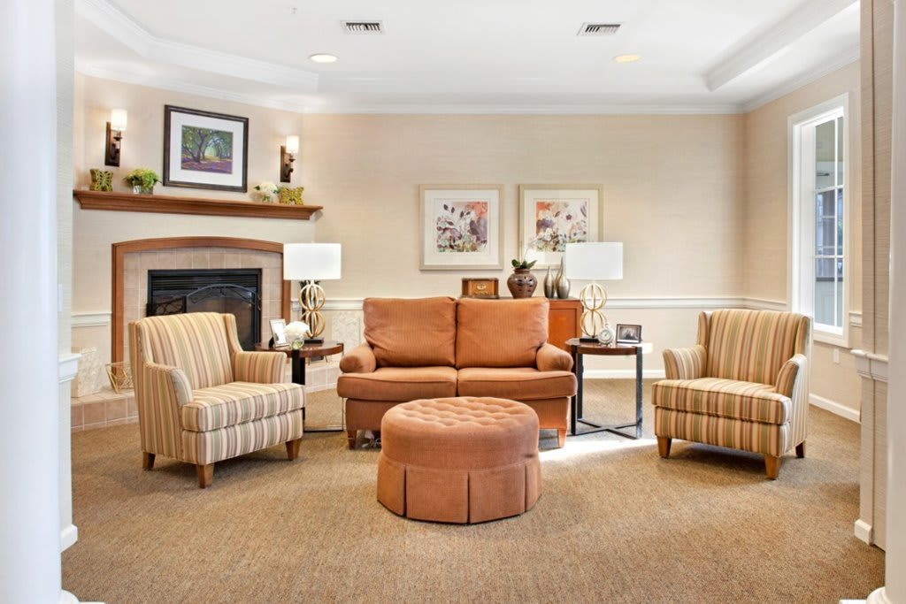 A cozy living room with a sofa and armchairs, featuring a fireplace and decorative elements.