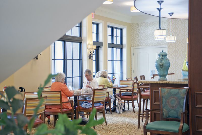 A group of seniors socializing in a cozy indoor seating area.