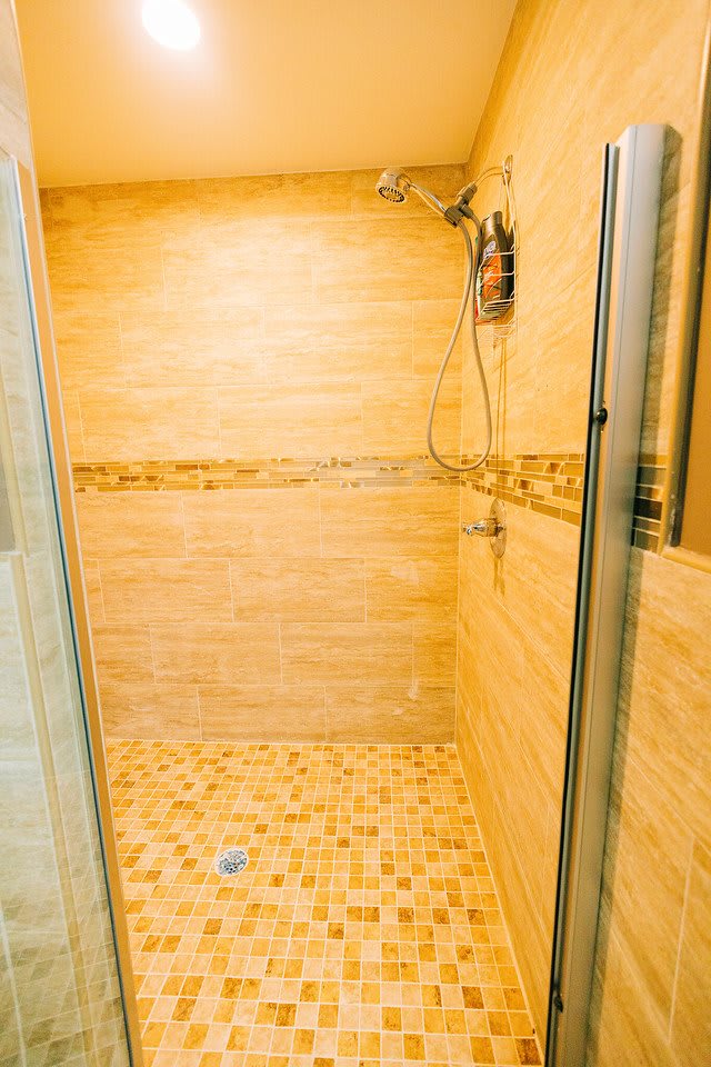 A modern shower with tiled walls and floor.