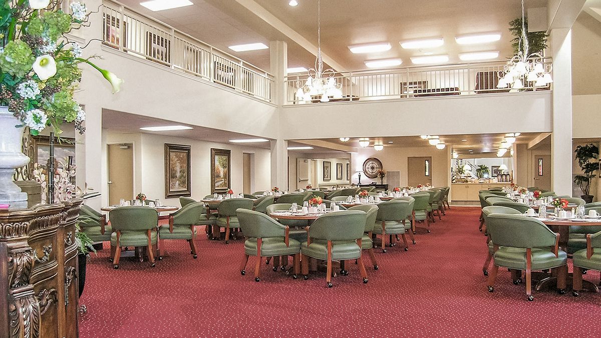 Spacious dining area with neatly arranged tables and chairs on a red carpet.