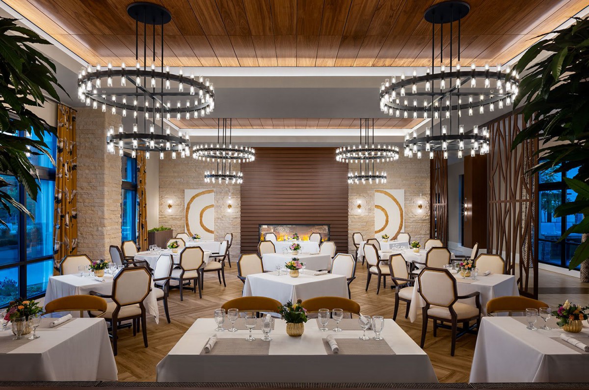 An elegantly designed restaurant interior featuring chandeliers and neatly arranged tables.