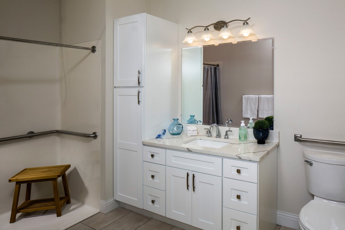 A modern bathroom with a white vanity, mirror, and stylish lighting fixtures.