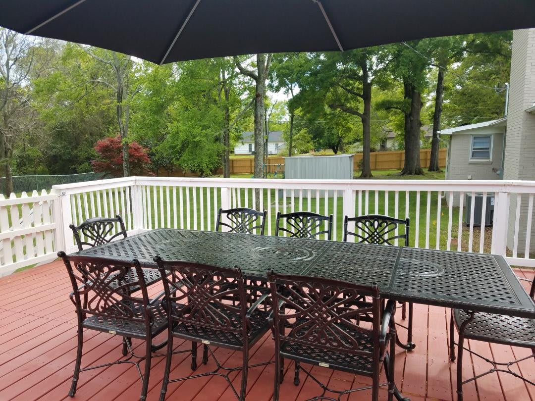 A backyard patio features a metal table with matching chairs and a large umbrella.