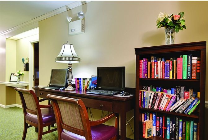 A cozy office space with a desk, computers, and a well-stocked bookshelf.