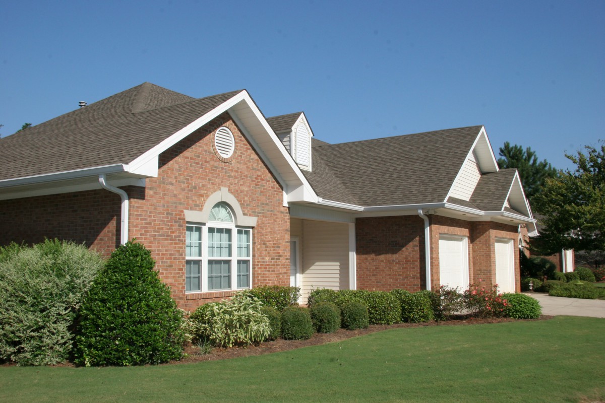 A suburban brick house with a well-maintained lawn and landscaped garden.