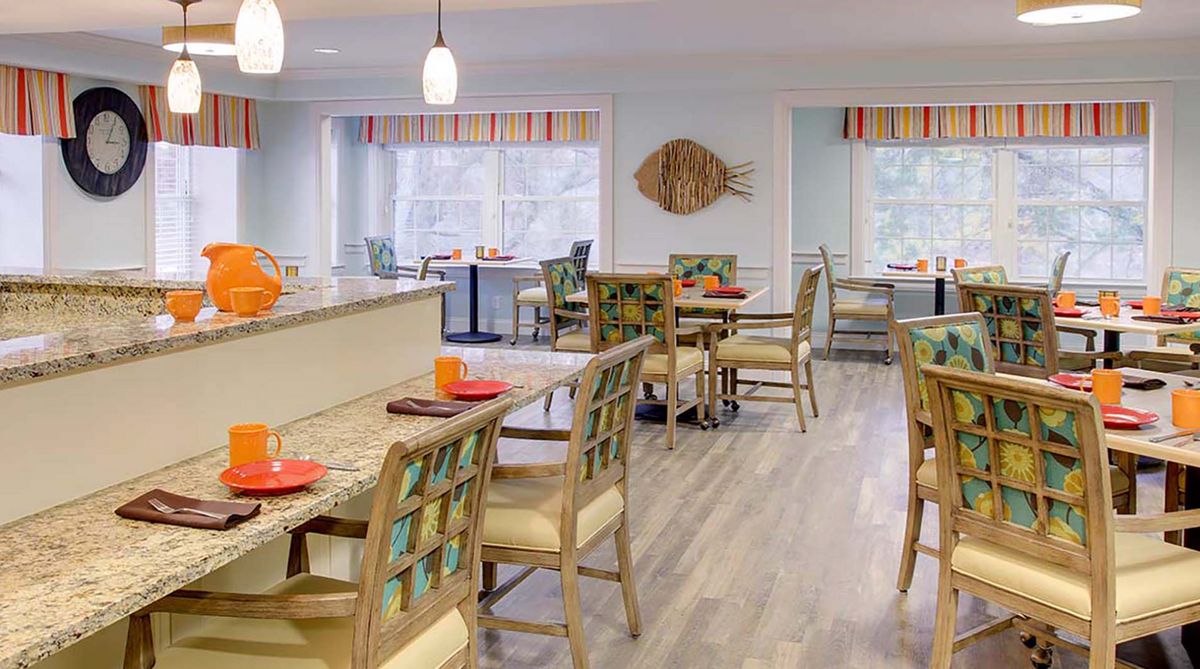 A modern dining area with neatly arranged tables and chairs, featuring pendant lighting and contemporary decor.
