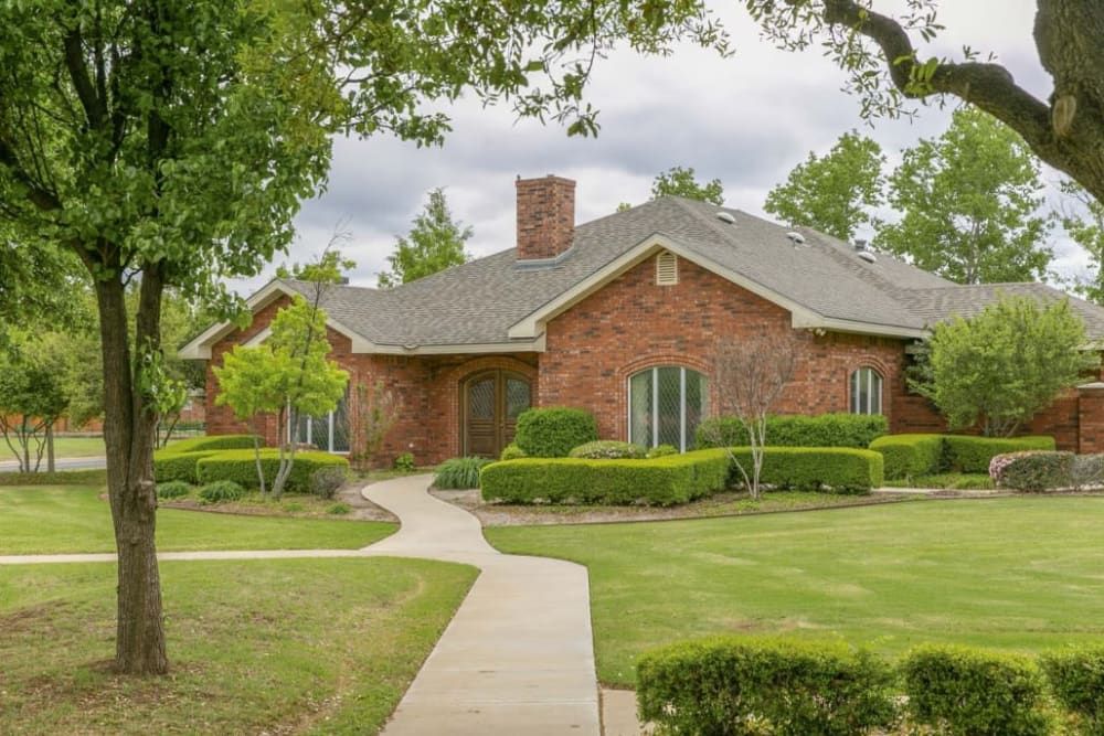 A suburban brick house with a well-maintained lawn and a winding pathway.