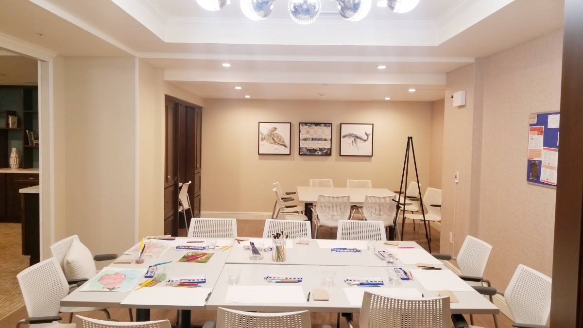 An art classroom with neatly arranged tables and chairs, equipped with drawing materials and art supplies.