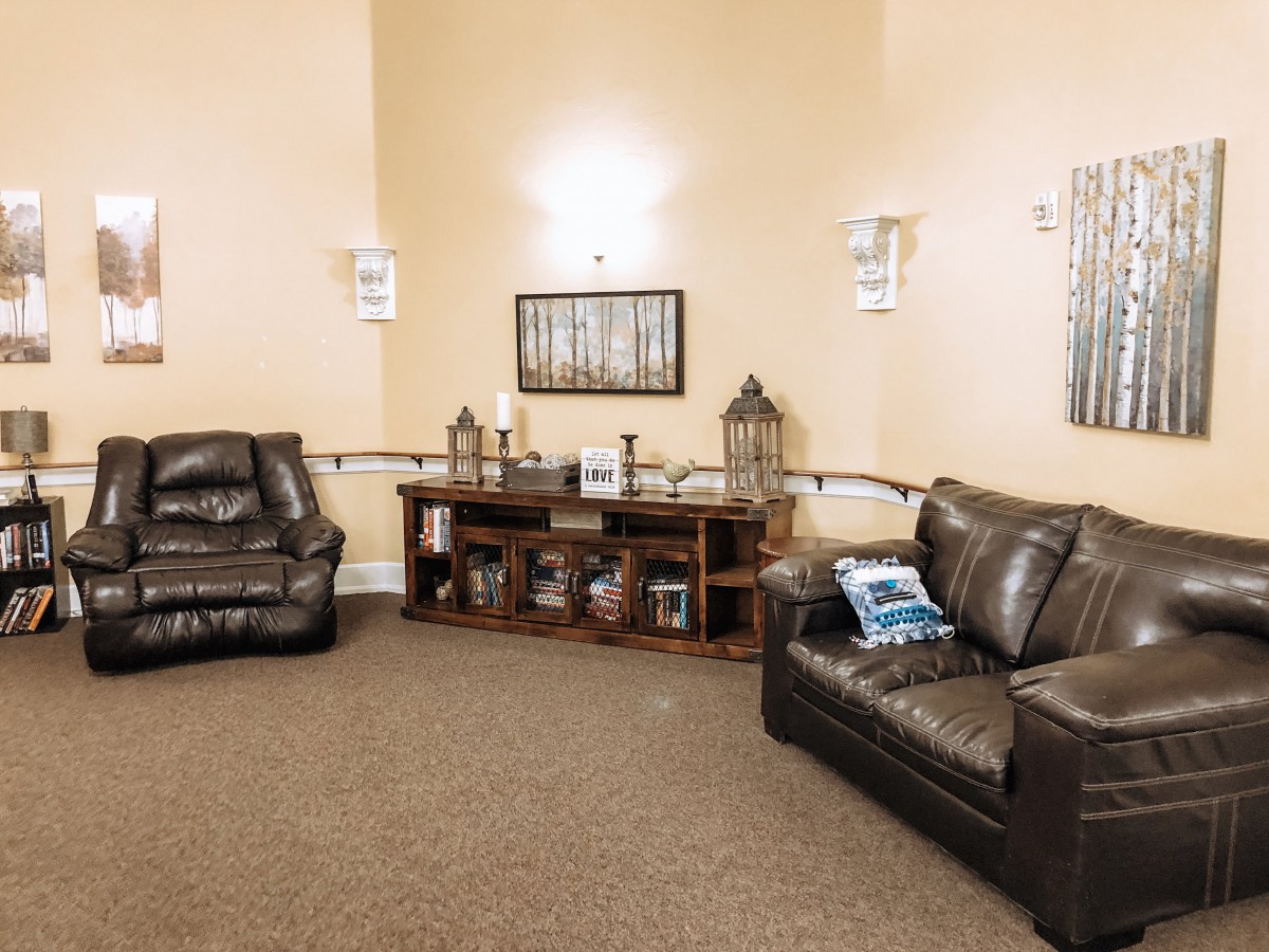 A cozy living room with dark leather sofas and a central shelf decorated with lanterns and framed artwork.