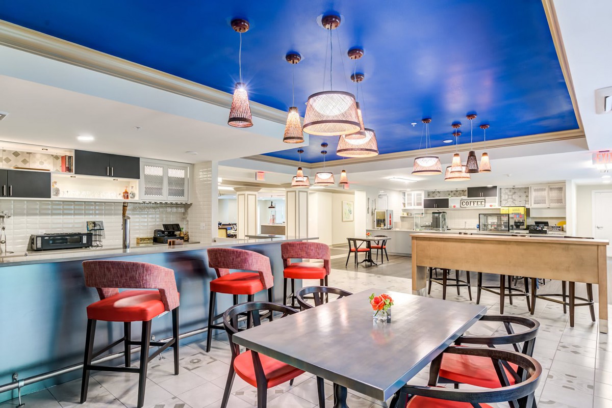 A modern restaurant interior with red chairs, a blue ceiling, and stylish lighting fixtures.