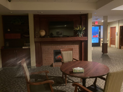 A cozy lobby area featuring a fireplace, wooden table, and chairs.