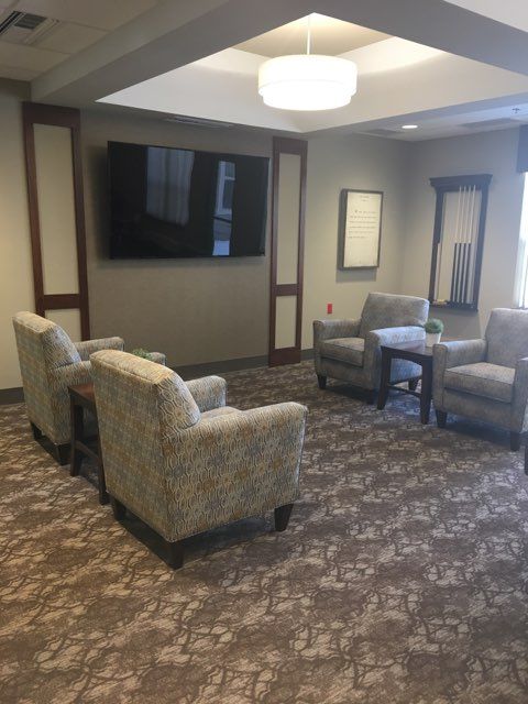 A cozy lounge area with comfortable chairs and a large television on the wall.