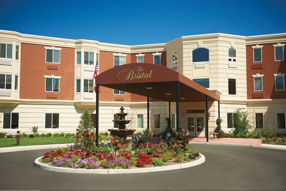 A hotel entrance with a landscaped garden and fountain.