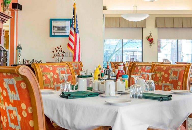 A dining area with a neatly set table, featuring an American flag in the background.