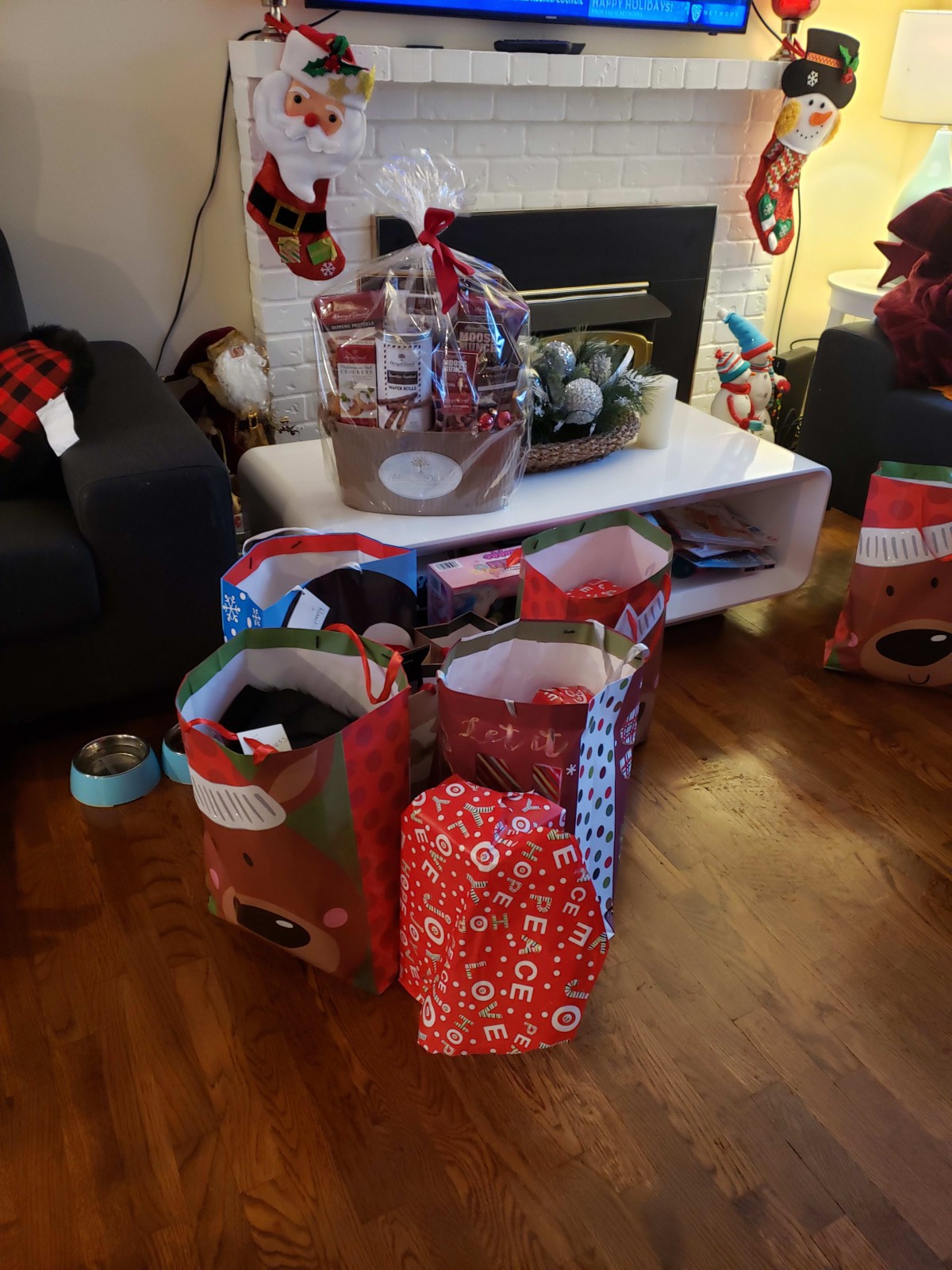 A cozy living room decorated for Christmas with gifts wrapped in festive paper around a coffee table.