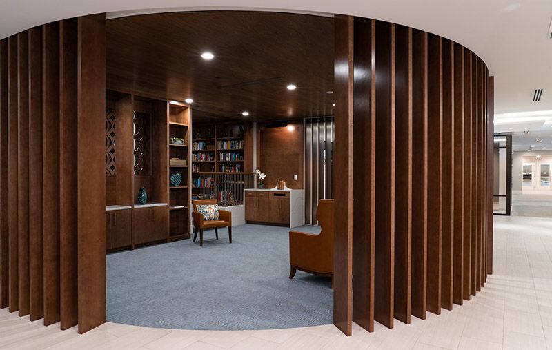 A modern library with wooden bookshelves and a cozy reading area.