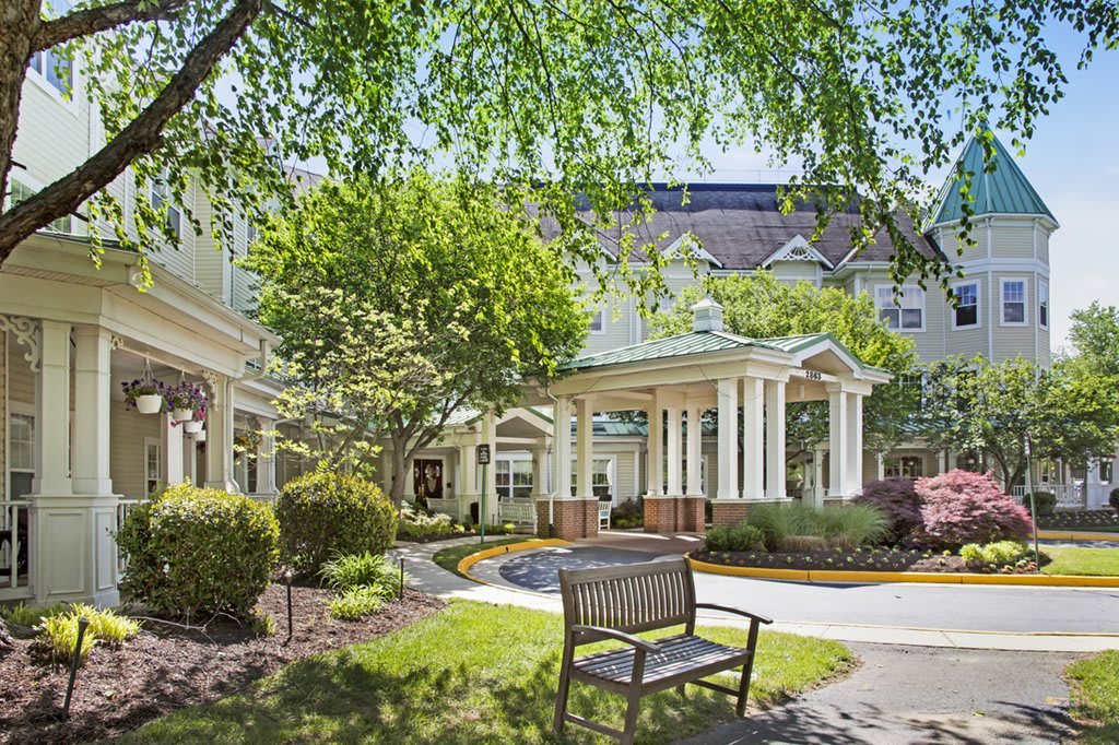 A cozy garden area with a bench in front of a large building featuring classic architecture.