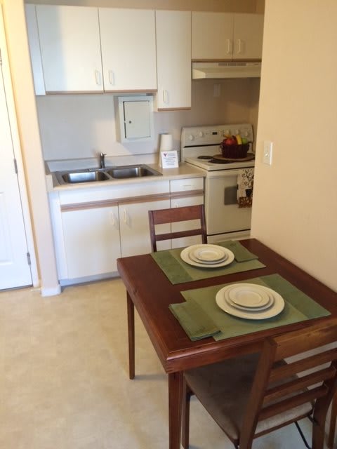 A small apartment kitchen with a dining table set for two.