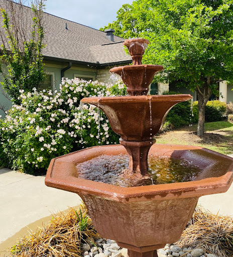 A charming tiered fountain surrounded by vibrant greenery and blooming flowers.