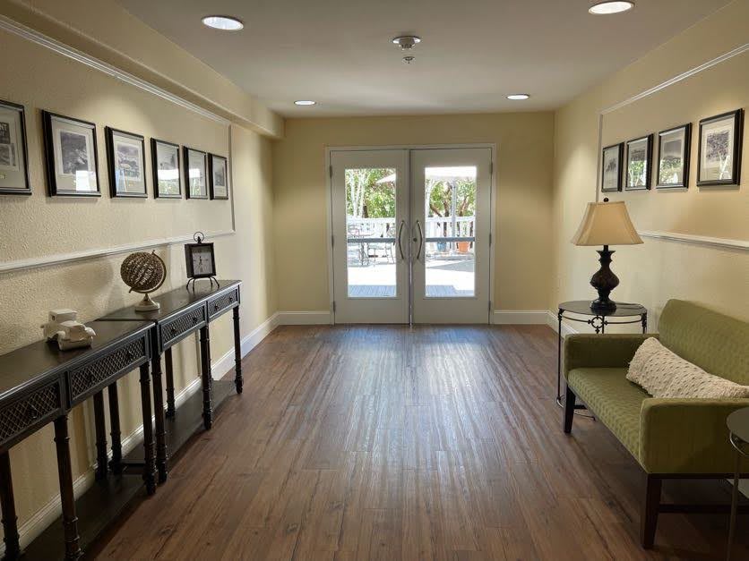A well-lit hallway with hardwood flooring, featuring decorated walls and a lamp on the side table.