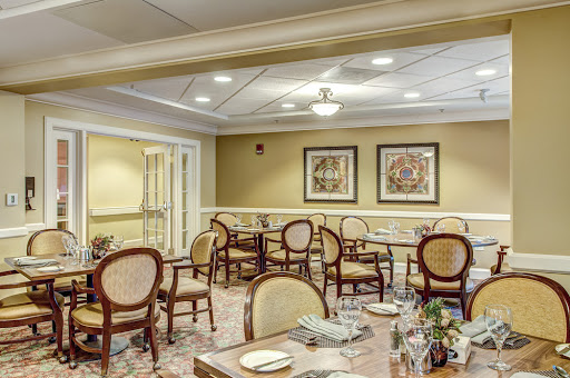 A cozy dining area featuring elegantly arranged tables and chairs, illuminated by soft lighting.