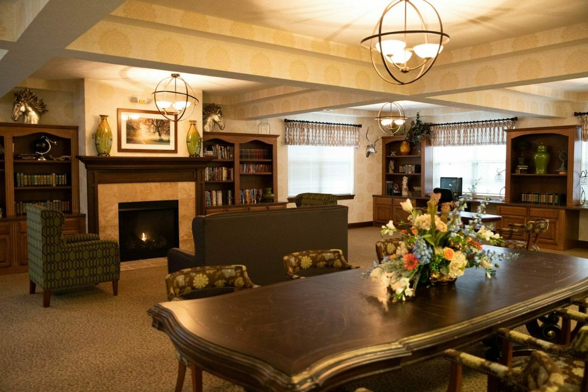 A cozy living room with a fireplace, bookshelves, and a dining table decorated with flowers.